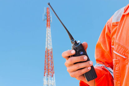 man with handheld radio with radio tower in the background