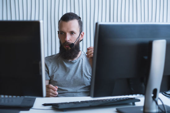 male on headset looking at computer screens