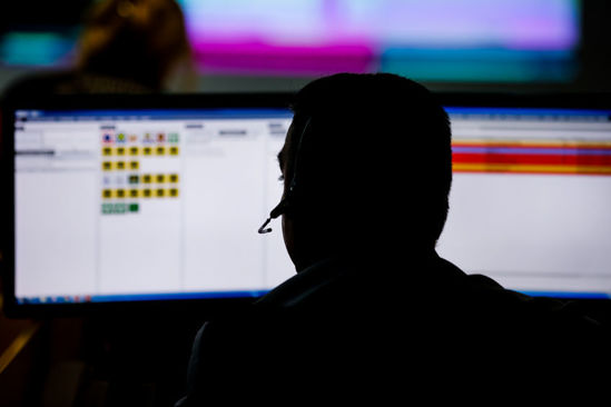 silhouette of person in front of computer screens